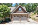 View of a two-car garage featuring stone accents and a basketball hoop in the driveway at 34 Laurel Ne Way, White, GA 30184