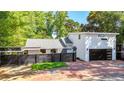 Modern home with black privacy fence, gray roof, brick driveway, mature trees and two-car garage at 1048 Indian Hills Pkwy, Marietta, GA 30068