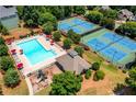 Aerial view showcasing community pool and tennis courts surrounded by mature trees at 4108 Wyndam Hill Dr, Suwanee, GA 30024