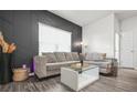Modern living room with a comfortable gray sofa, a decorative accent wall, and sleek wood floors at 4076 Sonoma Wood Trl, Decatur, GA 30034