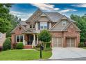 Charming two-story home with a well-manicured lawn, stone and brick facade, and two-car garage at 3150 Seven Oaks Dr, Cumming, GA 30041