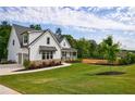 Beautiful white farmhouse with manicured lawn and stone accents at 130 Lapis Lake Pt, Fayetteville, GA 30215