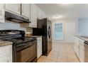 Galley kitchen with black appliances, tile floors, and white cabinets at 2341 Alden, Jonesboro, GA 30236