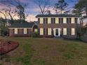 Inviting two-story brick home at twilight, showcasing its classic architecture and warm ambiance at 4076 Shady Nw Cir, Lilburn, GA 30047