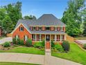Beautiful two-story brick home featuring a covered front porch, mature landscaping, and a well-maintained lawn at 2535 Winthrope Way, Lawrenceville, GA 30044