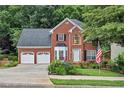 Lovely brick home with a two-car garage, beautiful lawn, American flag, and meticulously landscaped front yard at 2018 Township Dr, Woodstock, GA 30189