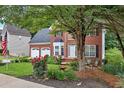 Traditional brick home featuring an American flag, a well-maintained lawn, and colorful flower beds at 2018 Township Dr, Woodstock, GA 30189