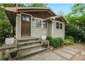 A close up on this charming bungalow features a wood door, stone steps, and green siding at 677 Holmes Nw St, Atlanta, GA 30318