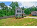 Well-maintained gray two-story home with a spacious lawn, complemented by mature trees and a wooden fence at 6375 Eidson Dr, Cumming, GA 30041