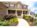 Inviting front porch with a stone accent wall and decorative landscaping at 6585 Canyon Cv, Cumming, GA 30028