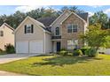 Traditional home featuring a well-kept lawn, double garage, and stone facade at 211 Millstone Dr, Hampton, GA 30228