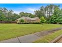Well-maintained single-story home with stone accents, manicured landscaping, and lush green lawn at 7030 Mandevilla Ln, Douglasville, GA 30135
