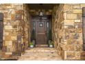 Inviting covered front entry features stone accents, a rustic wood door and professional landscaping at 799 Wagon Trl, Woodstock, GA 30188