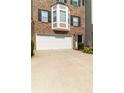 Close-up view of the townhome with a white garage door, brick facade, and a bay window at 6004 Turfway Park Ct, Sugar Hill, GA 30518