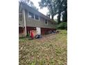 Exterior of a home with a white door leading to a basement and a small yard with some debris at 2708 Beacon Dr, Atlanta, GA 30360