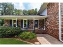 Covered front porch with brick accents, rocking chairs, and a charming entrance to the home at 5778 Little Oak Trl, Stone Mountain, GA 30087