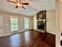 Inviting living room featuring a stone fireplace, wood floors, and natural light from large windows at 186 Grapevine Dr, Douglasville, GA 30134