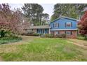 Charming two-story home with a manicured lawn and mature trees, showcasing curb appeal at 493 James Street Sw, Lilburn, GA 30047