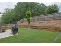 Large, grassy backyard with a retaining wall and privacy fence providing a serene outdoor space at 1267 Castleberry Dr, Buford, GA 30518