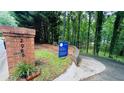 View of address and real estate sign on a quiet street surrounded by mature trees and landscaping at 2985 Heather Stone Way, Lawrenceville, GA 30043