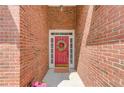 Close-up of a red brick entryway featuring a vibrant red door with decorative wreath and a patterned welcome mat at 3585 Berkeley Park Ct, Duluth, GA 30096