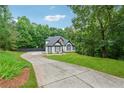View of home with well manicured lawn and a driveway leading up to a black and white trimmed home at 827 Holly Rdg, Canton, GA 30115