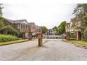 Gated community entrance with brick pillars, a wrought iron gate, and landscaped surroundings at 1666 Oakbrook Lake Dr, Norcross, GA 30093