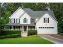 Charming two-story home with white siding, black shutters, a well-manicured lawn, and attached two car garage at 111 Bexley Ln, Douglasville, GA 30134