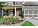 Inviting front porch with stone accents, a well-manicured garden bed, and an attached two-car garage at 4495 Hedgewood Dr, Cumming, GA 30041