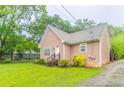 A charming, light pink home featuring manicured landscaping and verdant greenery on a cloudy day at 2378 Randall Ave, Lithonia, GA 30058
