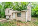 View of house with beige siding, a chimney, and mature trees in backyard at 5218 Tina Ct, Stone Mountain, GA 30083