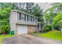 A split-level home showcasing a stone facade, attached garage, and well-maintained landscaping at 4766 White Oak Path, Stone Mountain, GA 30088