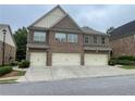 View of the exterior of the townhome with a three-car garage, brick facade, and covered entrance at 805 Pleasant Hill Nw Rd # 53, Lilburn, GA 30047