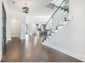 Stylish foyer with glass-railed staircase, dark wood floors, and open layout leading to a modern kitchen at 115 Thome Dr, Alpharetta, GA 30022