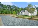 View of the luxury home, showcasing a brick-paved road, mature trees, and manicured landscaping enhancing the curb appeal at 115 Thome Dr, Alpharetta, GA 30022