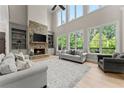Bright living room with a stone fireplace, built-in shelves, and large windows overlooking a lush backyard at 6625 Baywood Run, Cumming, GA 30041
