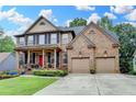 Brick home features a well-maintained lawn, an inviting covered front porch, and a two-car garage at 2612 Back Creek Chase, Dacula, GA 30019