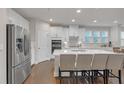 Modern kitchen with white cabinets, stainless steel appliances, island with breakfast bar, and hardwood floors at 267 Snow Owl Way, Lawrenceville, GA 30044