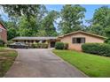 Ranch style home featuring a long driveway, brick facade, manicured shrubs, and mature trees at 3946 Flakes Mill Rd, Decatur, GA 30034