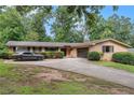 Ranch-style home with an attached garage, long driveway, a brick facade, and trimmed shrubs at 3946 Flakes Mill Rd, Decatur, GA 30034