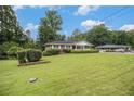 Expansive front yard features a brick house with lush greenery, manicured hedges, and mature trees at 4125 Lindsey Dr, Decatur, GA 30035