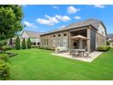 A well-maintained backyard features a covered patio, lush green lawn, and mature landscaping at 2115 Creekstone Point Dr, Cumming, GA 30041