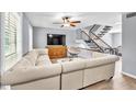 Inviting living room with a plush sectional sofa, modern ceiling fan, and staircase at 7307 Cardigan Cir, Sandy Springs, GA 30328