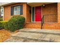 Close-up of a charming brick home entrance featuring a bright red door, black iron railing, and well-maintained landscaping at 3312 Northcrest Rd # A, Atlanta, GA 30340