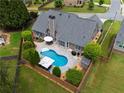 Aerial view of a private backyard featuring a kidney-shaped pool, patio with furniture, and landscaped surroundings at 4721 W Lakeshore Dr, Acworth, GA 30101