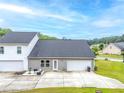 Back exterior view with a concrete patio, lawn, and two-car garage at 6330 Garden Cir, Douglasville, GA 30135