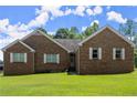 A brick home with shutters sits on a large lawn with blue skies in the background at 3950 Chattahoochee Rd, Cumming, GA 30041