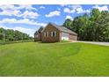 A brick home is displayed on a large lawn with an attached two-car garage at 3950 Chattahoochee Rd, Cumming, GA 30041