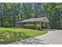 Ranch home with brick, carport, and driveway in wooded setting at 4774 Saint Bernard Sw Dr, Lilburn, GA 30047