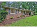 Traditional brick home featuring shutters, covered porch, and manicured landscaping at 4774 Saint Bernard Sw Dr, Lilburn, GA 30047